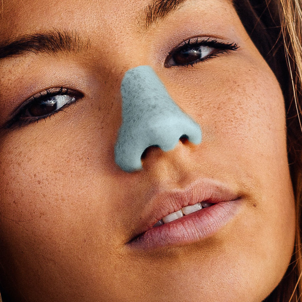 Zoomed in head of girl, tilted and displaying Nöz sunscreen on her nose in the blue tone. 